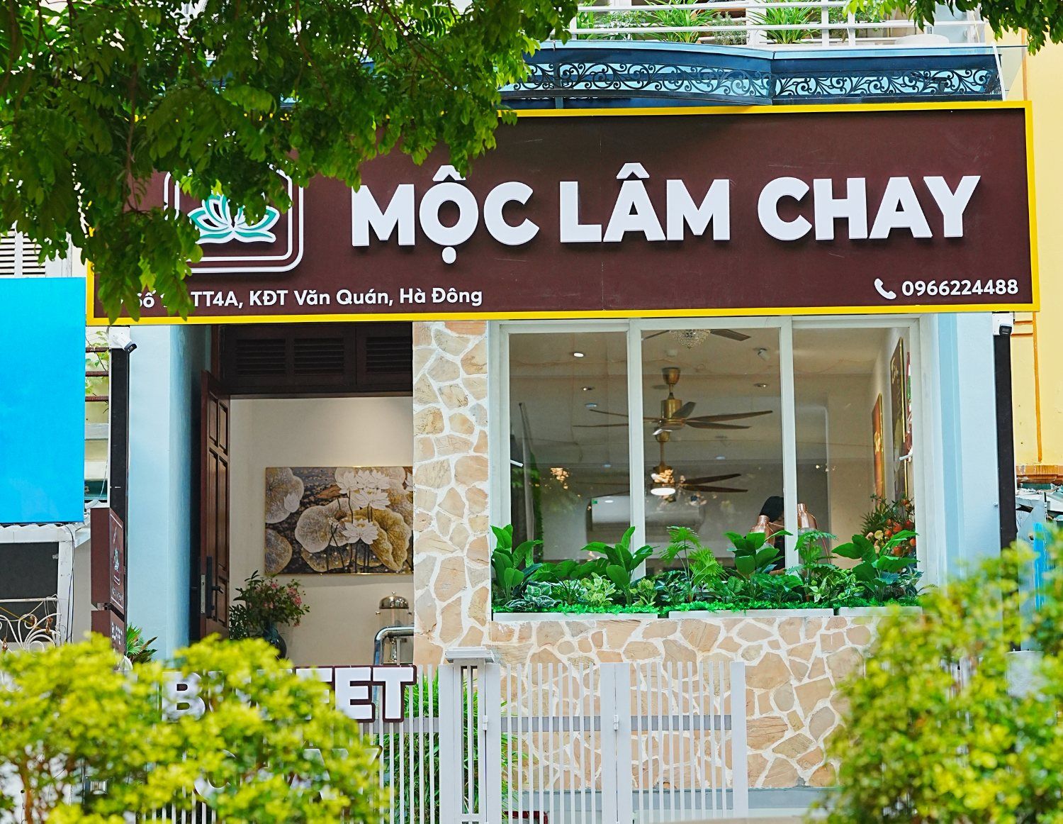 Mặt tiền Mộc Lâm Chay ban ngày, bồn cây xanh trước cửa kính